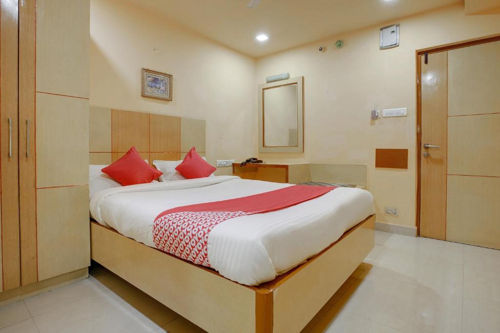 OYO Shanthaa Residency في Surūrnagar: غرفة نوم بسرير كبير ومخدات حمراء