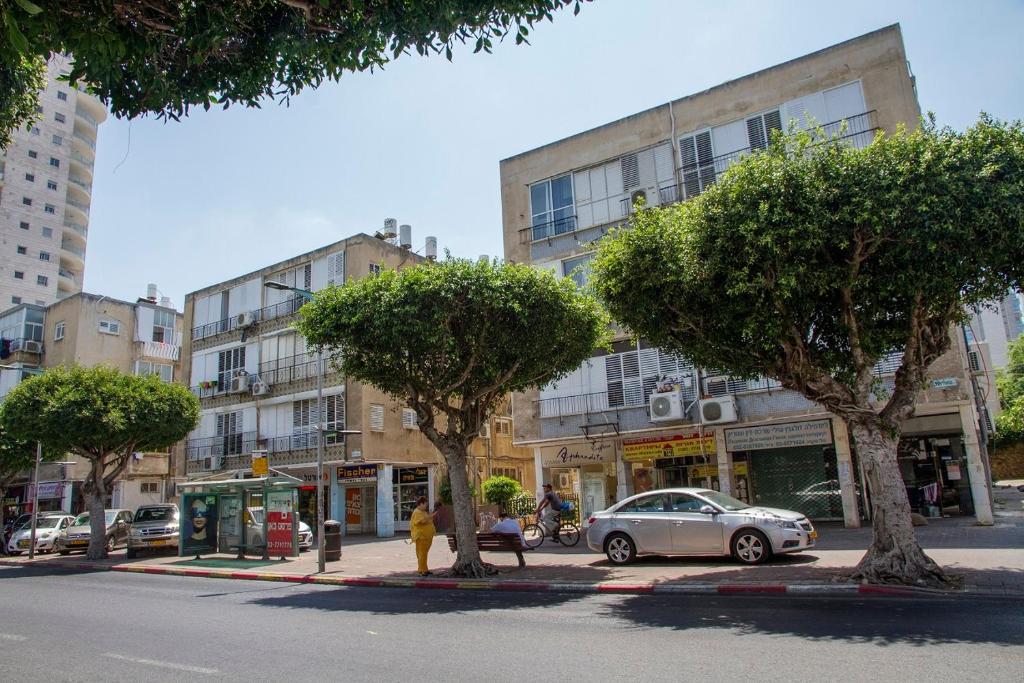 a city street with trees and a car parked on the street at Apartments4you Maria in Bat Yam