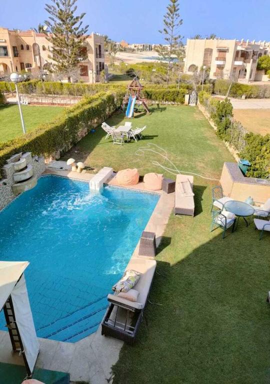 a swimming pool in a yard with a playground at فيلا بالكامل الساحل مارينا اطلاله فيو البحر in El Alamein