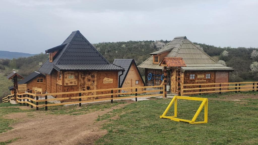eine Gruppe von Holzhütten mit gelbem Schild im Gras in der Unterkunft ETNO SELO VEZIROV RANČ in Sjenica