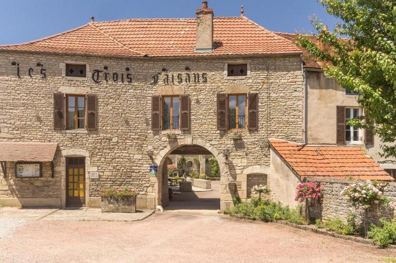 ein altes Backsteingebäude mit einem Torbogen davor in der Unterkunft Les Trois Faisans in Bligny-sur-Ouche