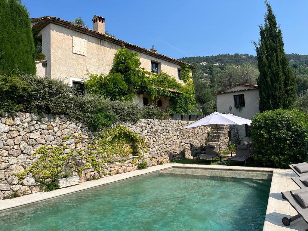 une maison avec piscine à côté d'un mur de pierre dans l'établissement PROCHE GRASSE - LE MAS de la MADONETTE, à Spéracèdes