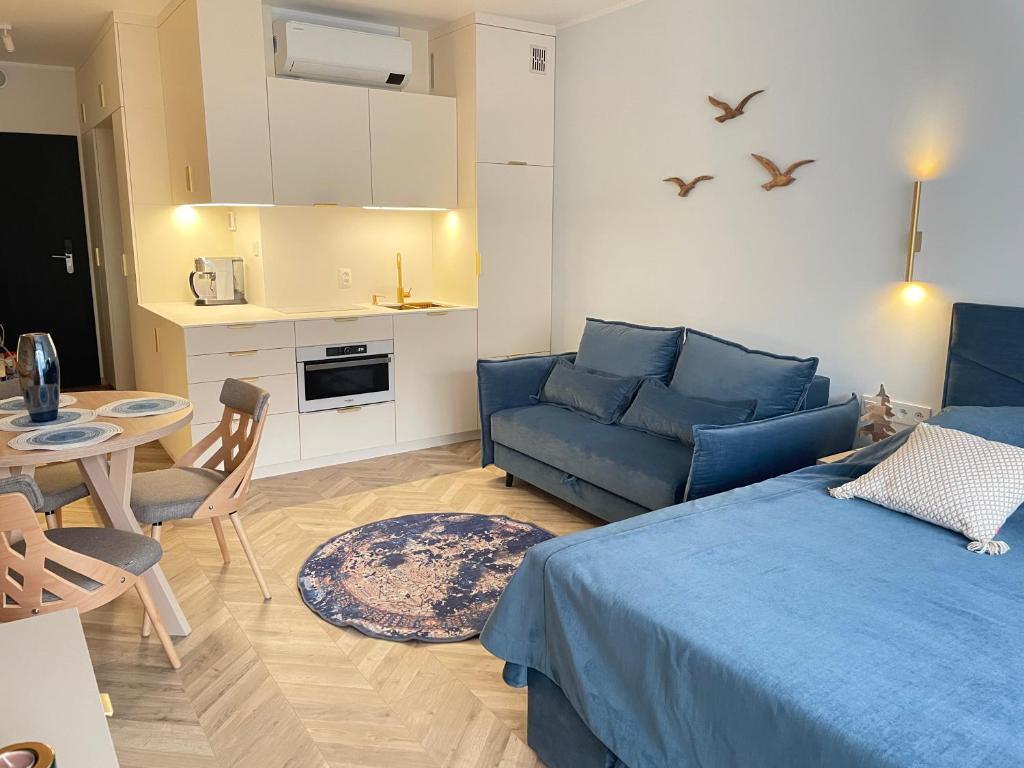 a living room with a blue bed and a kitchen at Apartament Morski Spokój Solny Resort in Kołobrzeg