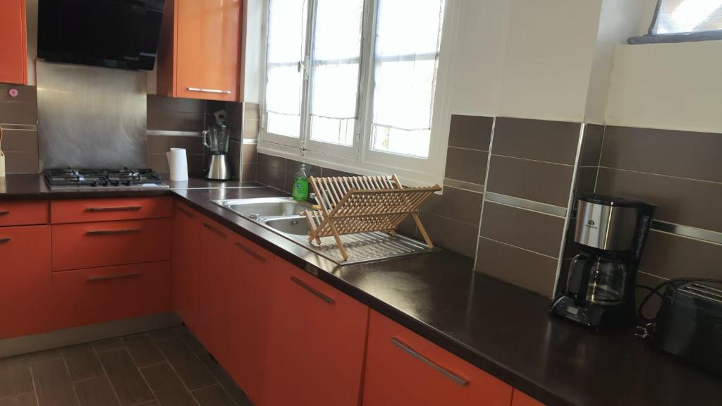 una pequeña cocina con armarios rojos y fregadero en Bel appartement, Bry- sur- Marne, en Bry-sur-Marne