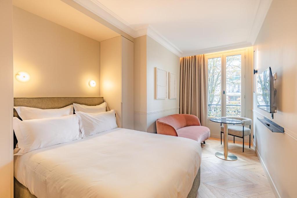 um quarto de hotel com uma cama e uma cadeira em Maison du Moulin Vert em Paris