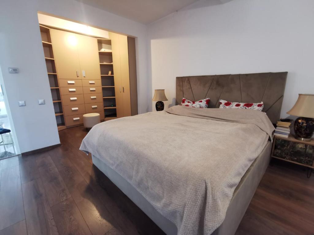 a bedroom with a large bed with a wooden floor at Residence TRL - Otopeni in Otopeni