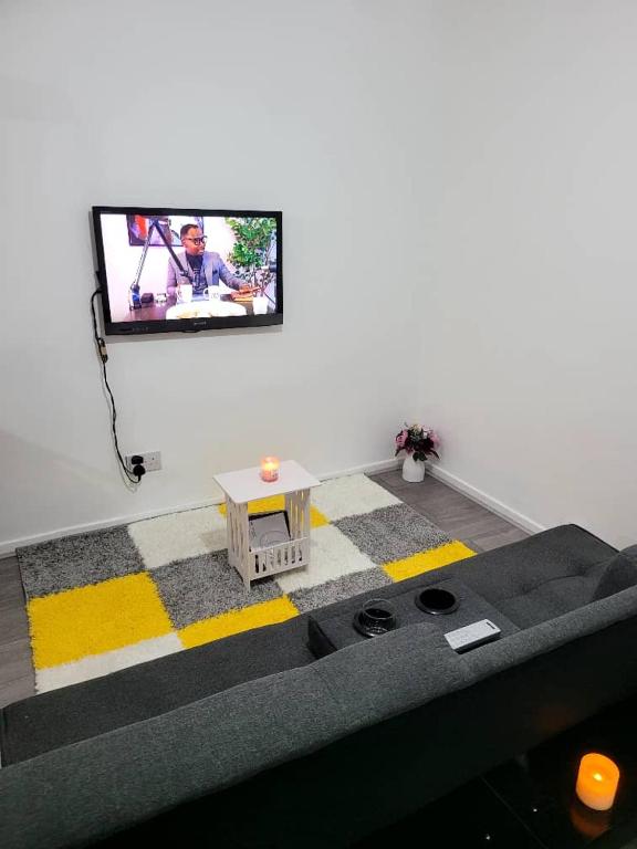 uma sala de estar com uma televisão de ecrã plano na parede em Venicci Suites em Londres