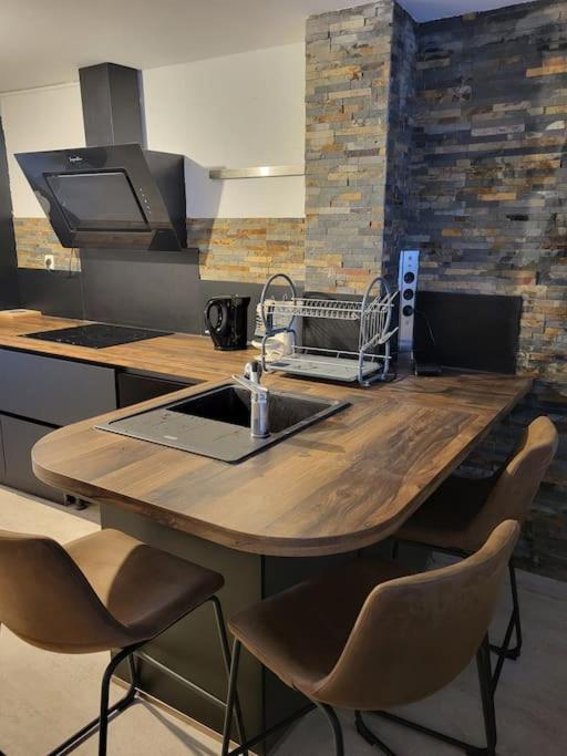 - une cuisine avec une table en bois, un évier et des chaises dans l'établissement Bel appartement avec Balnéo, à Sainte-Marie-aux-Mines