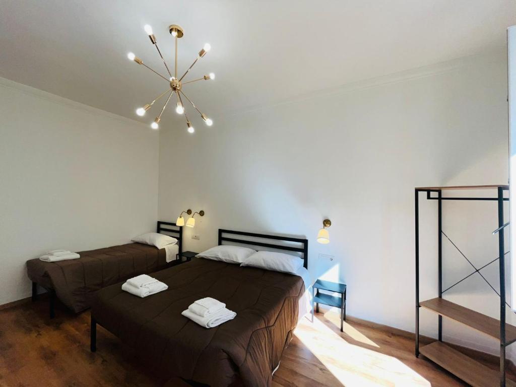 a bedroom with two beds and a chandelier at Prime Rooms Oriani in Florence