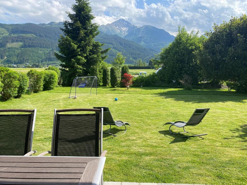 two chairs and a bench in a field with mountains at Chalet Panoramablick Zell am See in Zell am See