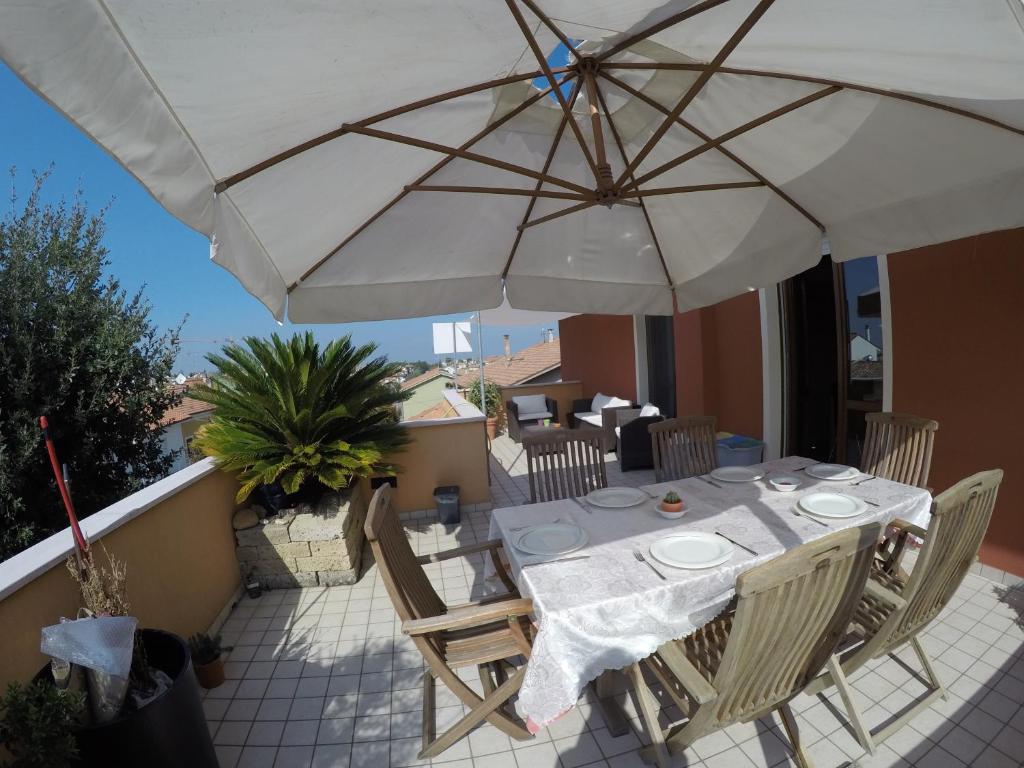 Una mesa y sillas con una sombrilla en un patio. en Lellolocations - Attico Via Villetta, en San Costanzo