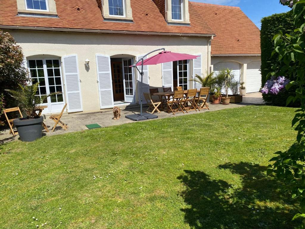a patio with a table and a pink umbrella at Domaine de la coqueraine in Ouistreham