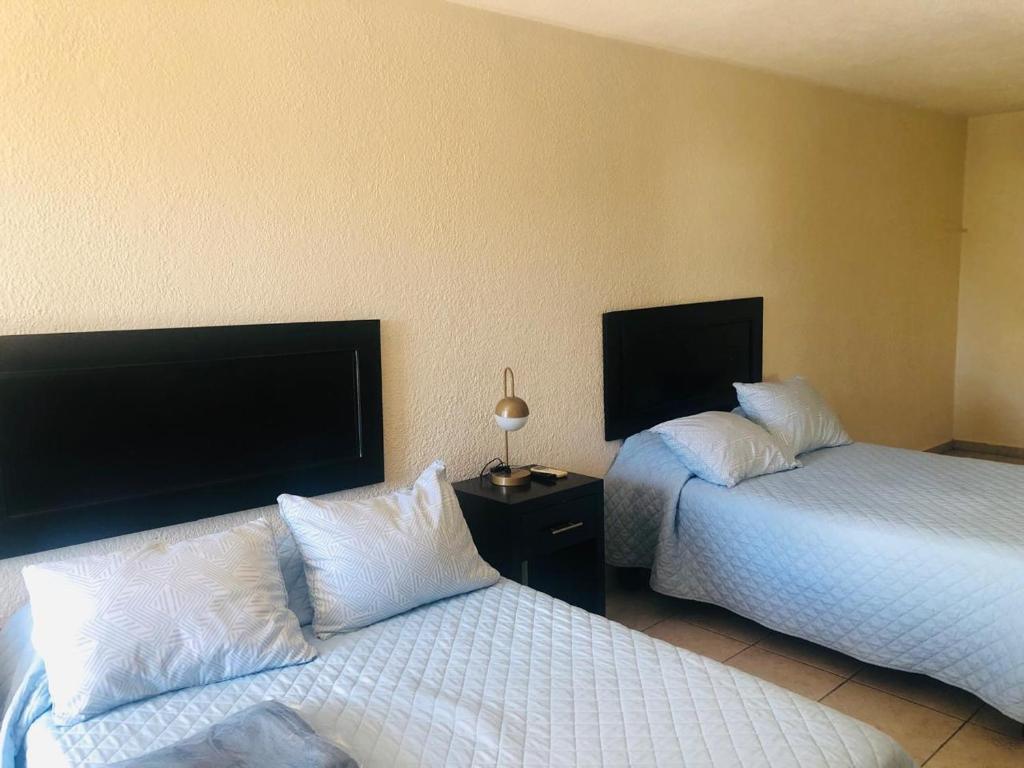 um quarto de hotel com duas camas e uma televisão em Hotel nuevo atardecer em Cabo San Lucas