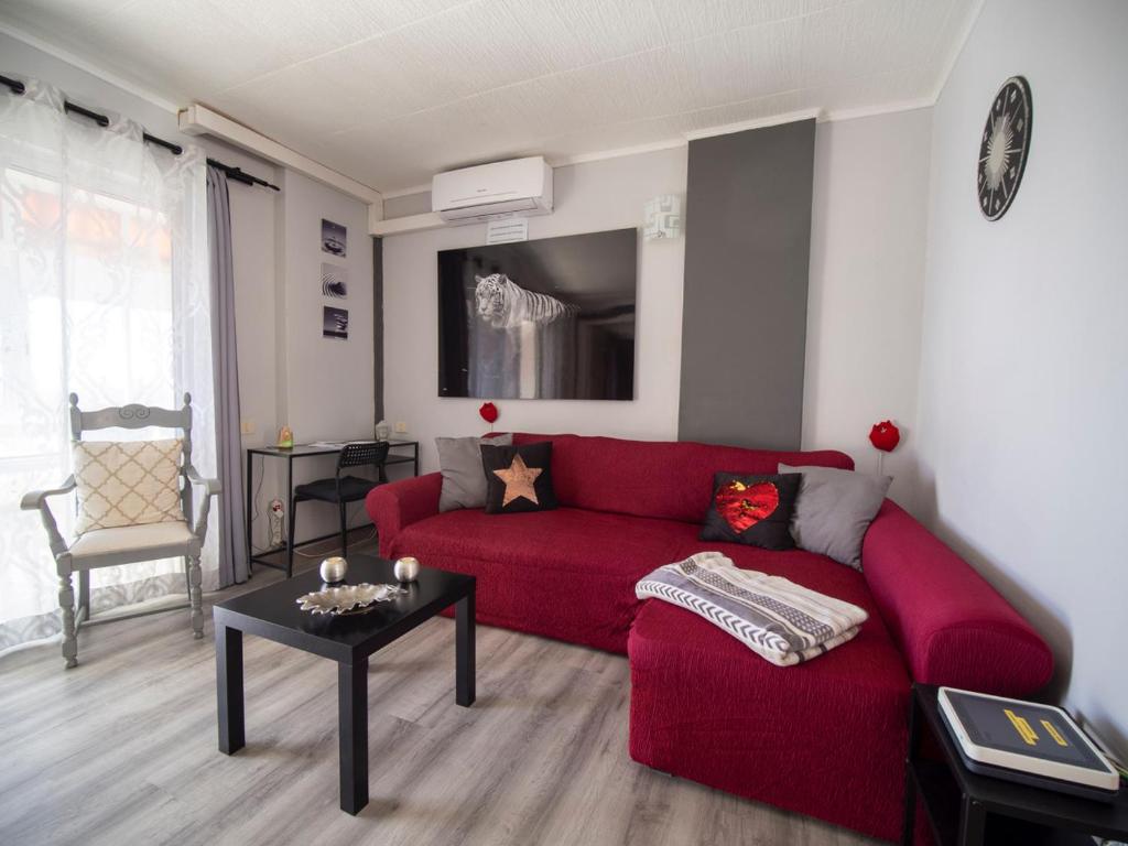 Laurent Suite في سانتا كروث دي تينيريفه: غرفة معيشة مع أريكة حمراء وطاولة