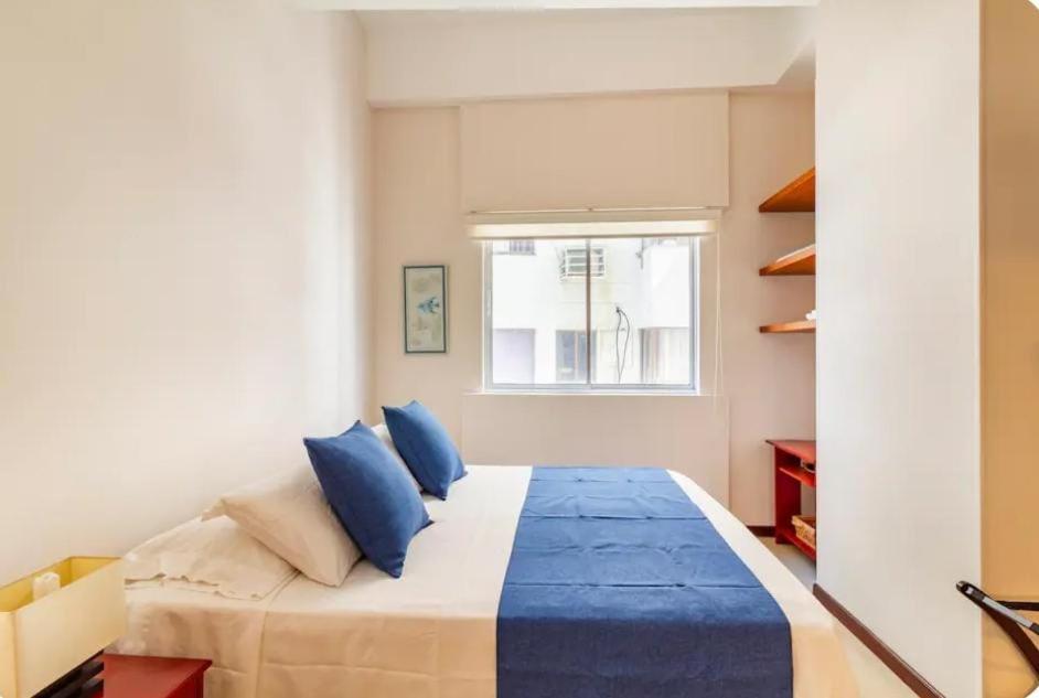a bedroom with a bed with blue pillows and a window at Vista al lago en Cartagena in Cartagena de Indias