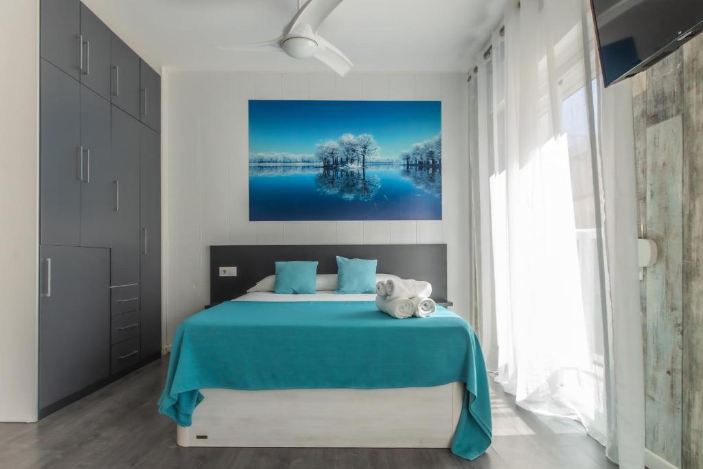 een slaapkamer met een blauw bed en een schilderij aan de muur bij Estudio con balcones 2ºA playa76 in Torremolinos