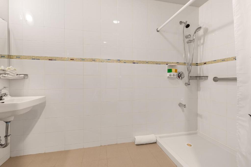 ein weißes Badezimmer mit Dusche und Waschbecken in der Unterkunft LIC Hotel in Queens