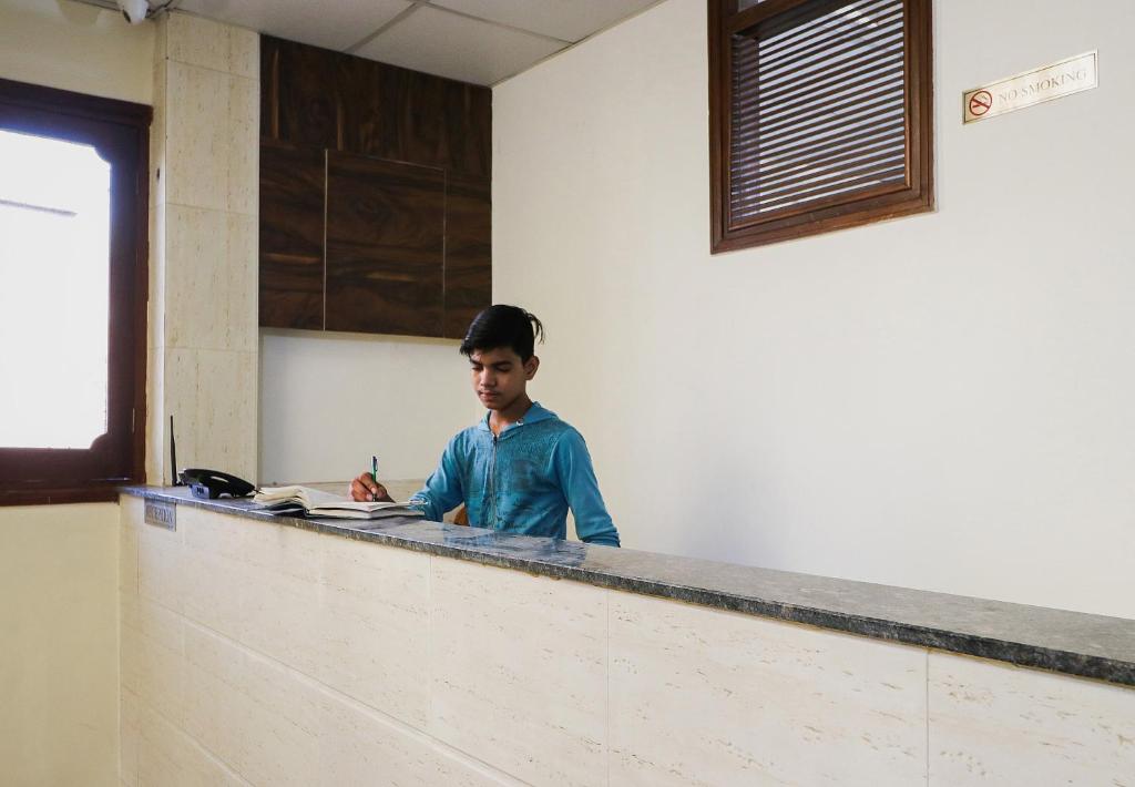 Un uomo in piedi dietro un bancone in una stanza di OYO Hotel Rk Inn a Ludhiana