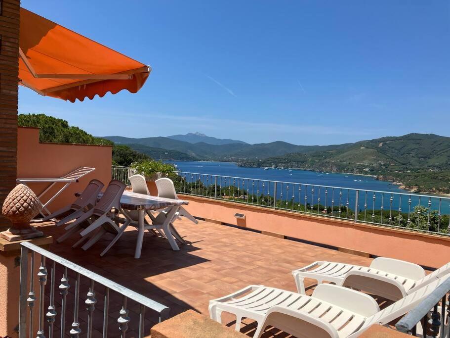 Un balcón con sillas y una mesa y vista al agua. en Villetta Zuccale III Natura e Vista Mozzafiato sul Mare, en Capoliveri