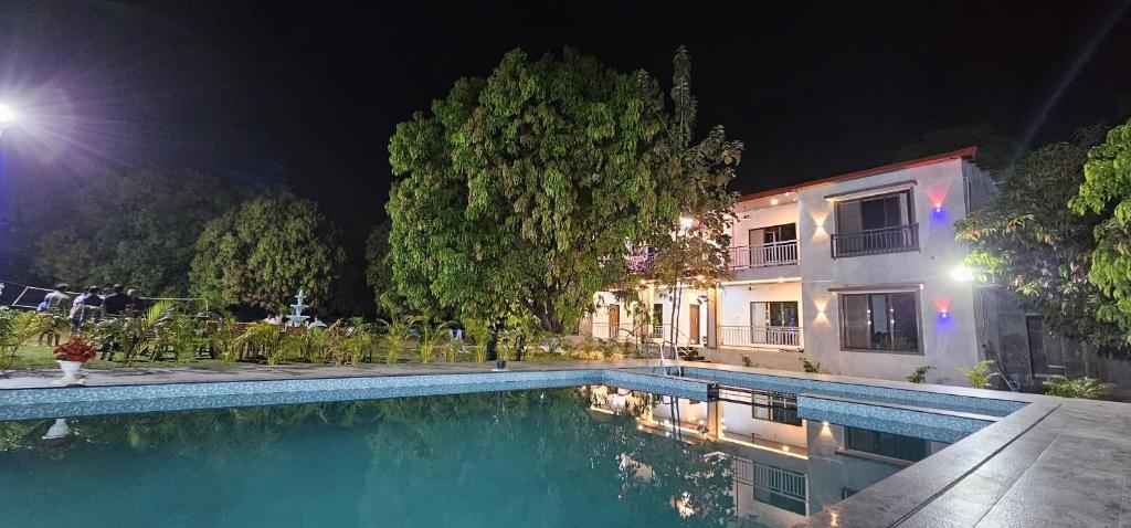a swimming pool in front of a building at night at The Riverland Farm in Karjat