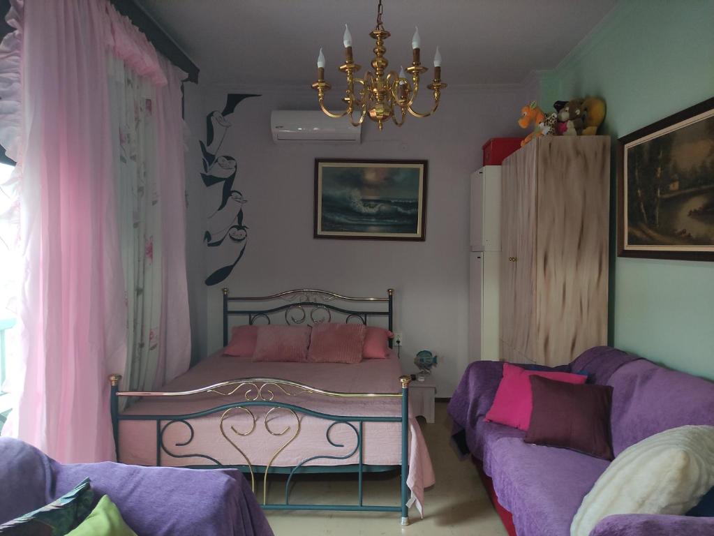 a bedroom with a bed and a couch and a chandelier at Kalys House in Kavála