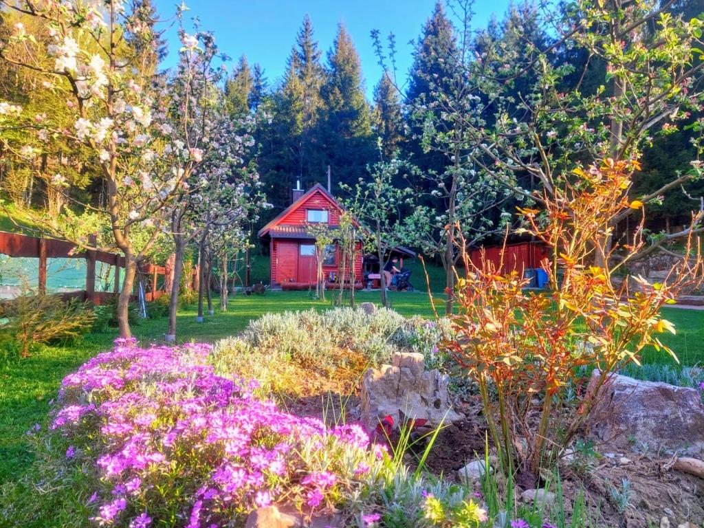 a garden with flowers in front of a red barn at Chalet Woody in Stara Sušica