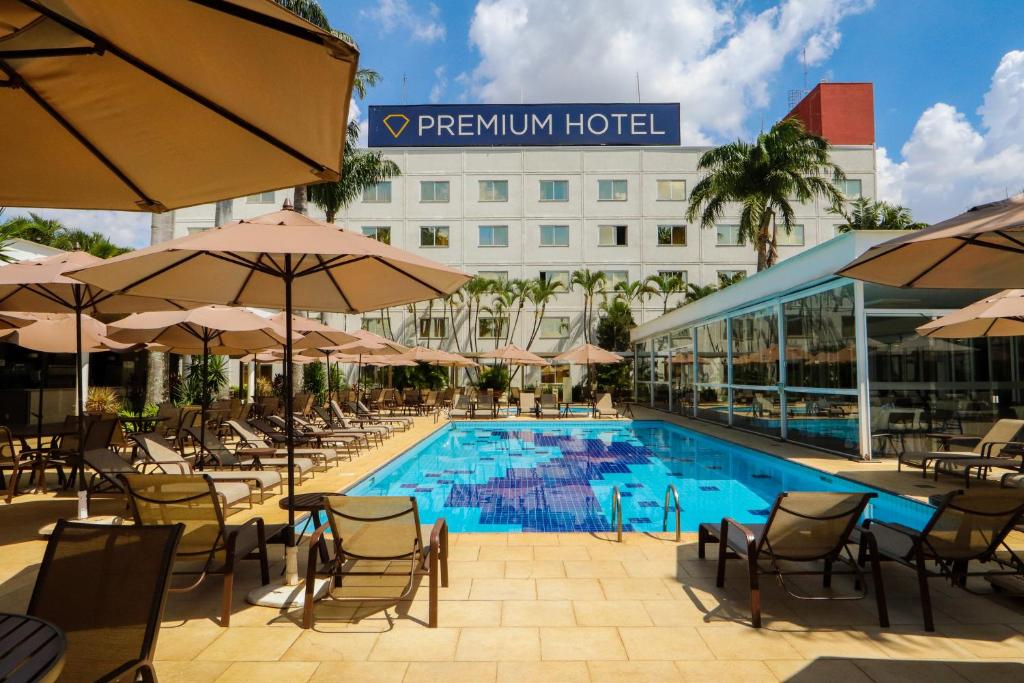 a pool with chairs and umbrellas next to a hotel at Hotel Premium Campinas in Campinas