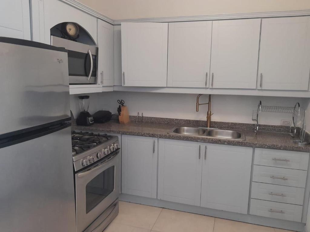a white kitchen with white cabinets and a sink at Se alquila apartamento amueblado en el centro de la ciudad in La Romana