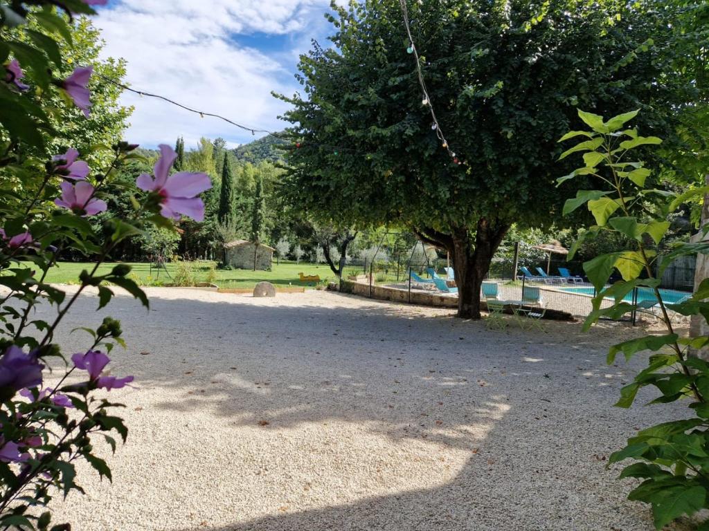 un parque con un árbol y una piscina en Le Moulin du Béal, en Aubres