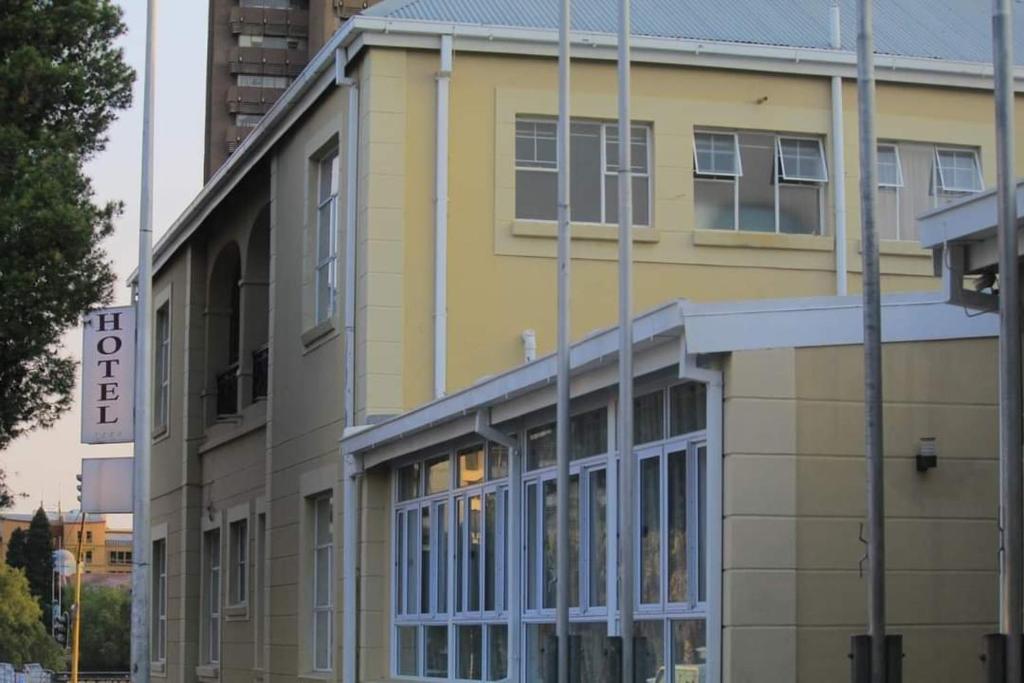 Bloemfontein的住宿－Sapphire Hotel Halevy Heritage，黄色的建筑,前面有标志