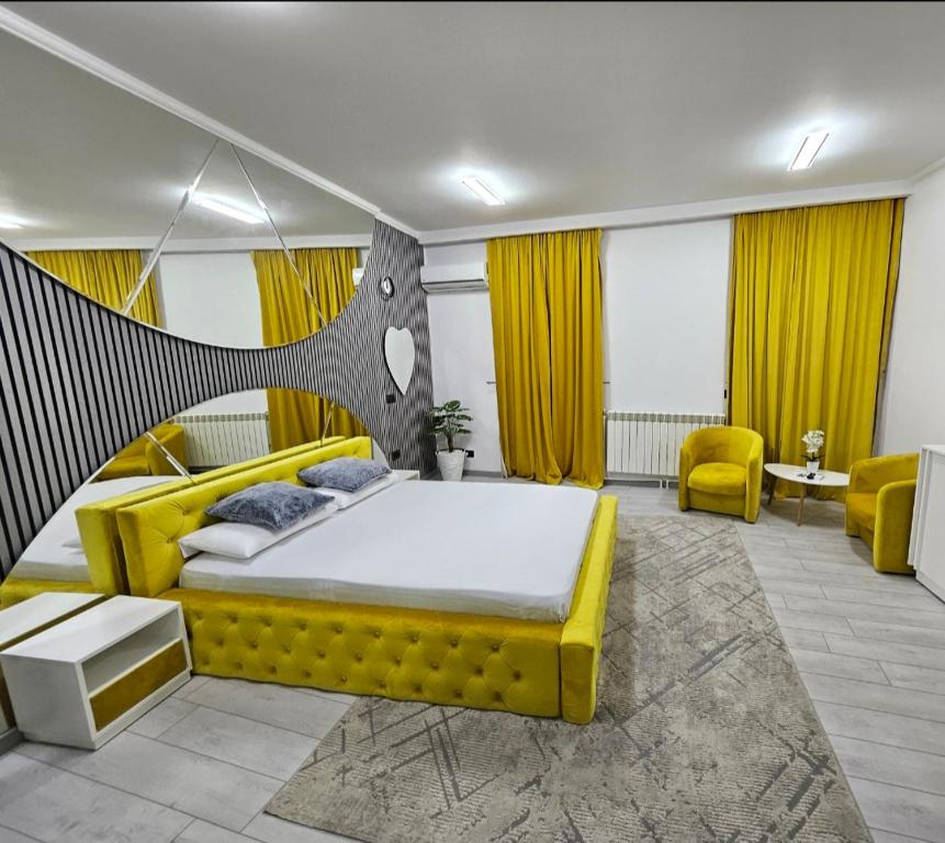 a bedroom with a large yellow bed and yellow chairs at Garsoniera Craiova Centru Vechi in Craiova