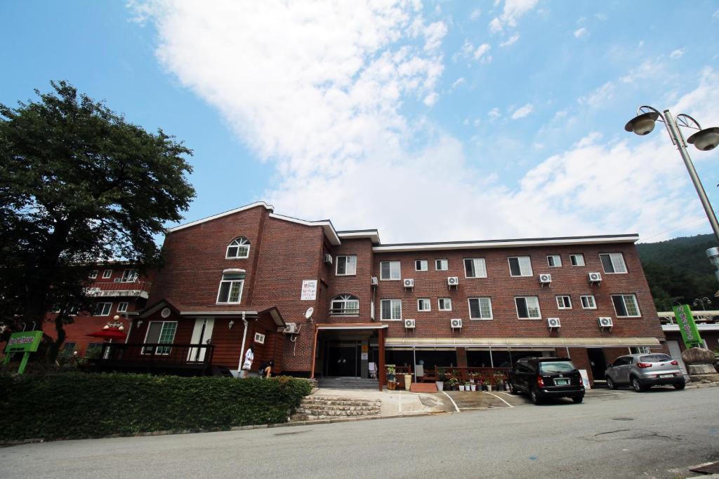 a large brick building with cars parked in front of it at The Red House in Sokcho