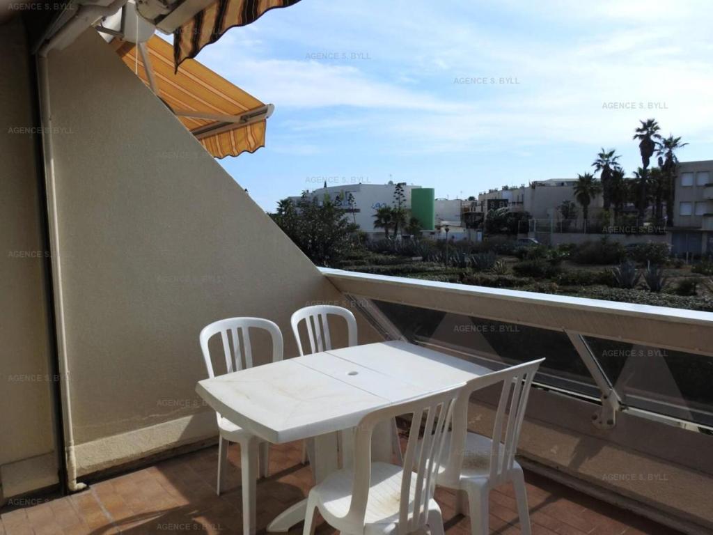 une table blanche et des chaises sur un balcon dans l'établissement Résidence Héliopolis Bâtiment Ab - Studio cabine 4 pers Héliopolis Bât. AB MAE-2954, au Cap d'Agde
