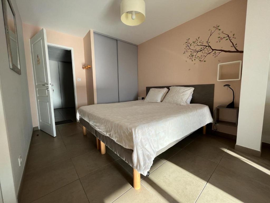 ein Schlafzimmer mit einem großen Bett mit weißer Bettwäsche in der Unterkunft Studio 1 avec piscine & vue sur la baie d'Ajaccio in Alata