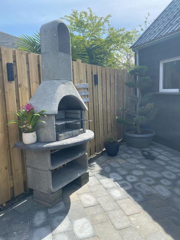 a stone oven in a backyard with a fence at gezellige cottage in zeeland in Sint Annaland