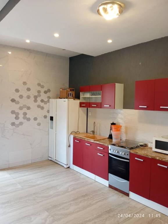 a kitchen with red cabinets and a white refrigerator at Havre de paix in Cotonou