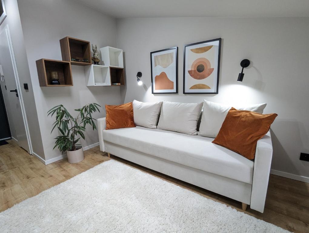 a white couch in a living room with paintings on the wall at Kolejowy Zajazd 2 in Łódź