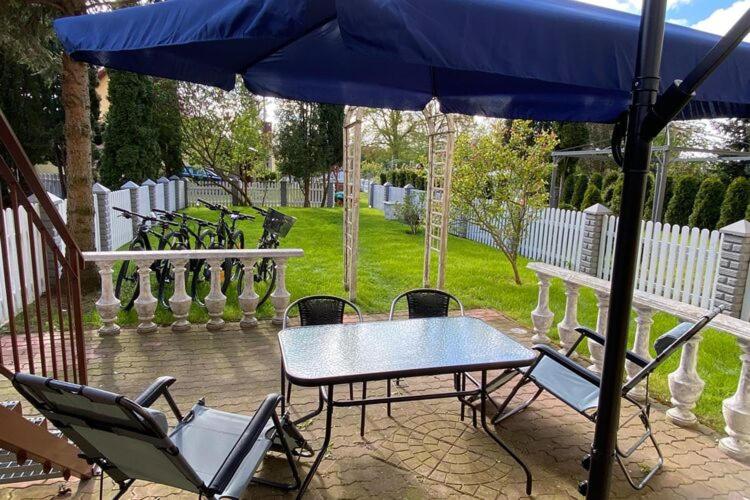 a table and chairs under an umbrella on a patio at Large holiday apartment with a garden in Stepnica in Stepnica