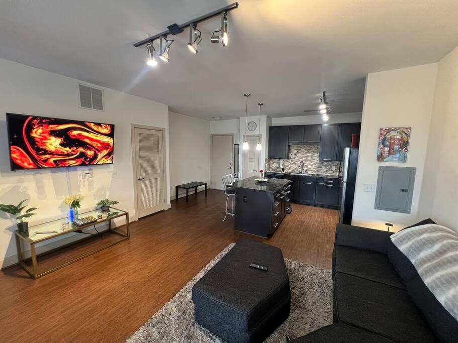 a living room with a black couch and a kitchen at BEAUTIFUL STUDIO 7MIN FROM THE GALLERIA MALL in Houston