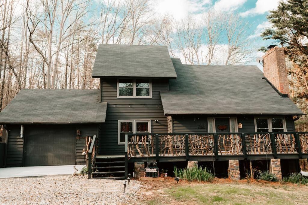 een zwart huis met een veranda en een balkon bij Luxury Mountain Getaway in Pickens
