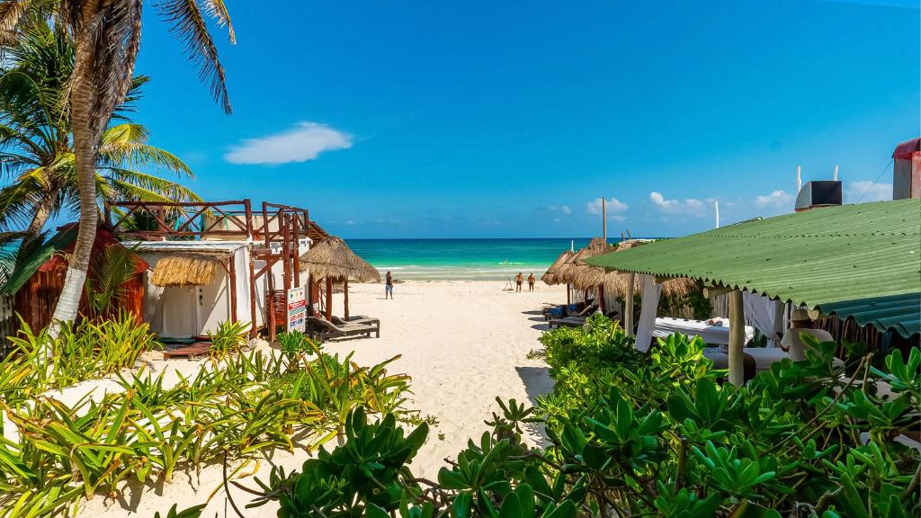 een strand met gebouwen en de oceaan op de achtergrond bij Chancabañita Tulum in Tulum