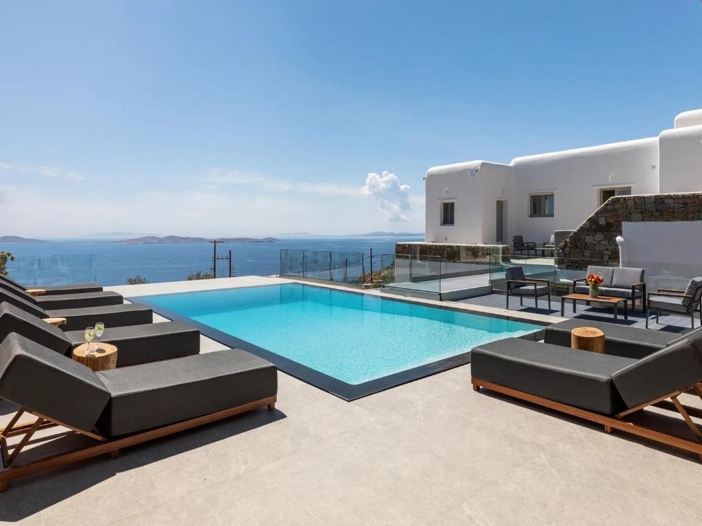 uma piscina com espreguiçadeiras e o oceano em Stunning Oceanview Mykonos Villa | 5 Bedrooms | Villa Perseus | Amazing Location Overlooking Sea & Private Pool | Faros em Fanari