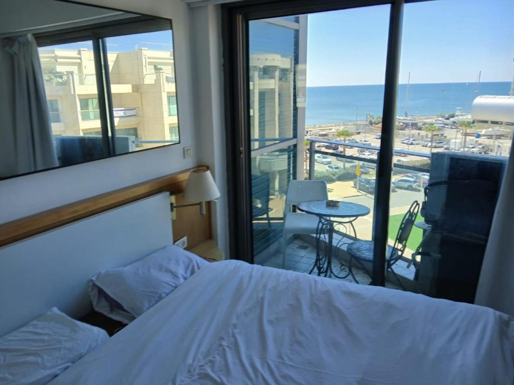 a bedroom with a bed and a view of the ocean at Hotel Apartment okeanos bamarina in Herzliya Pituah