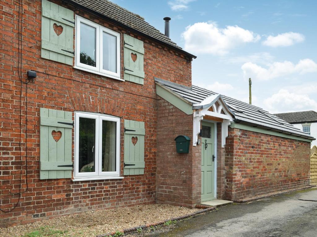 a brick house with a green door and windows at Victory Hall Cottage in Spilsby