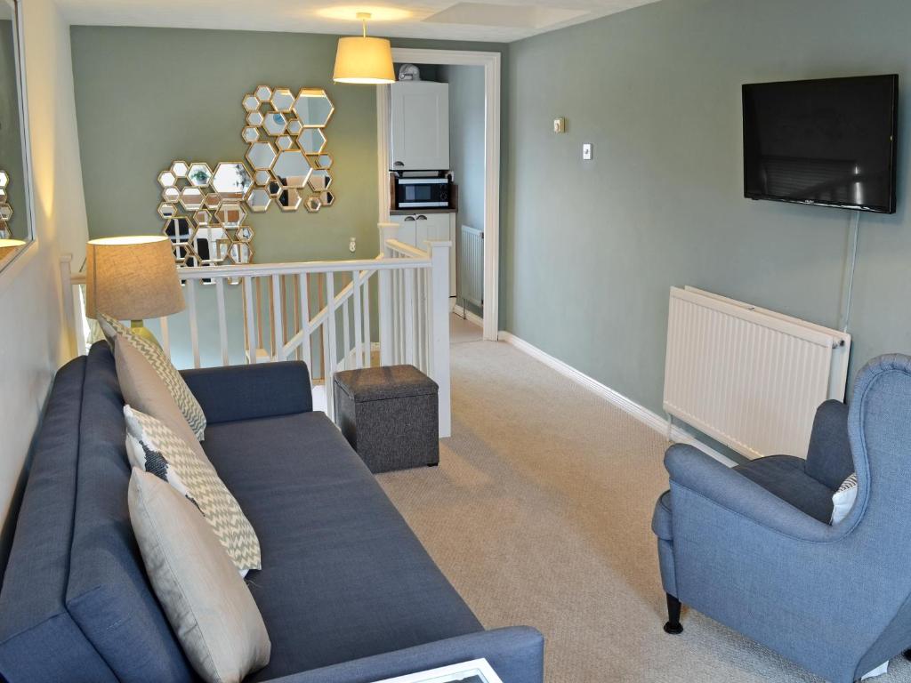 a living room with a blue couch and two chairs at Corner View in Broadstairs