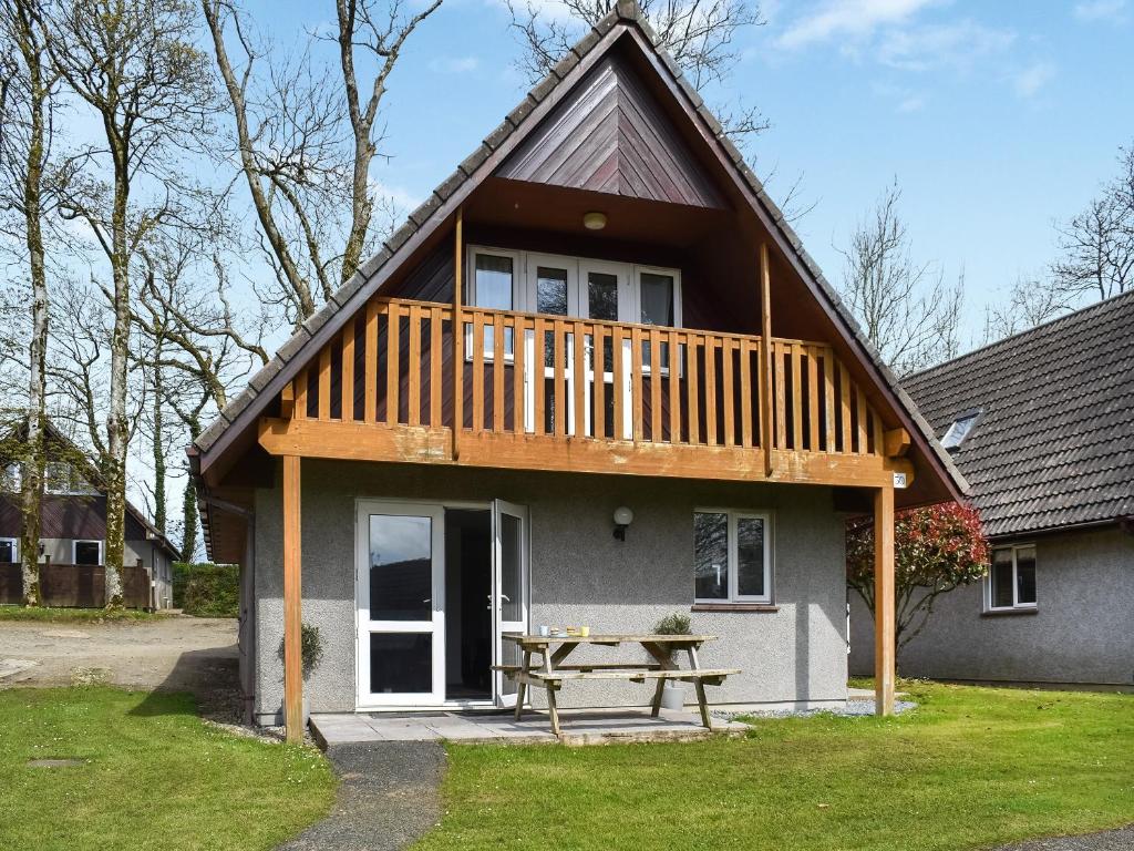 a house with a deck and a picnic table at Halcyons Rest in Saint Tudy