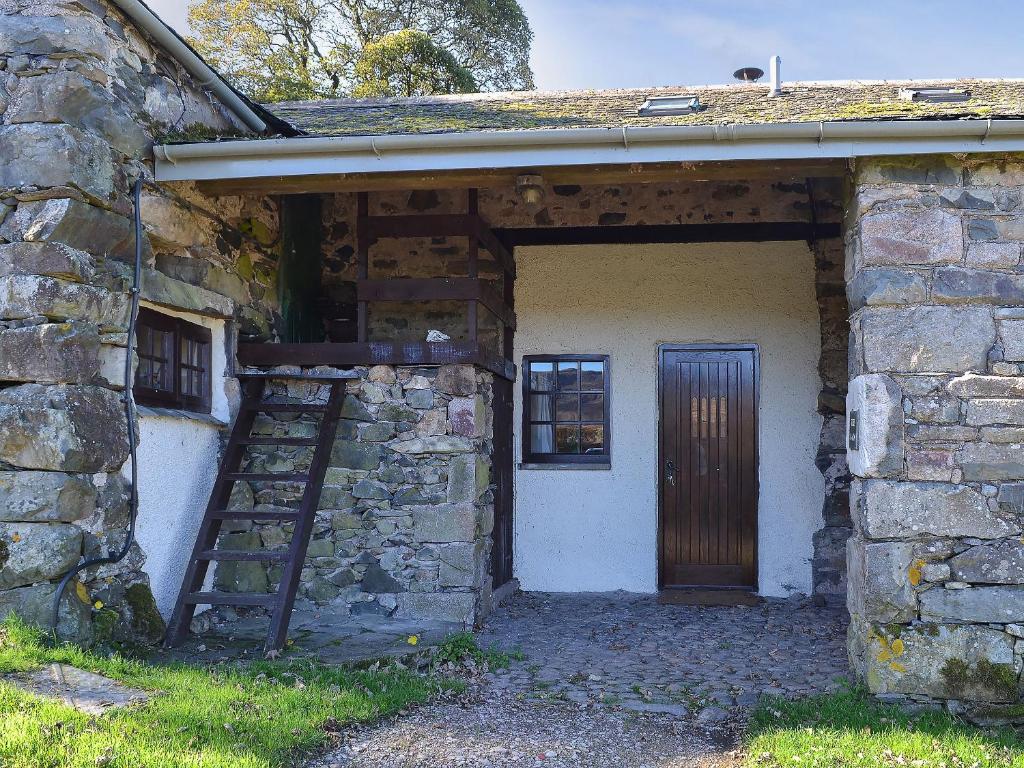 un antiguo edificio de piedra con una puerta de madera y una escalera en Birkerthwaite Barn-w41478 en Eskdale