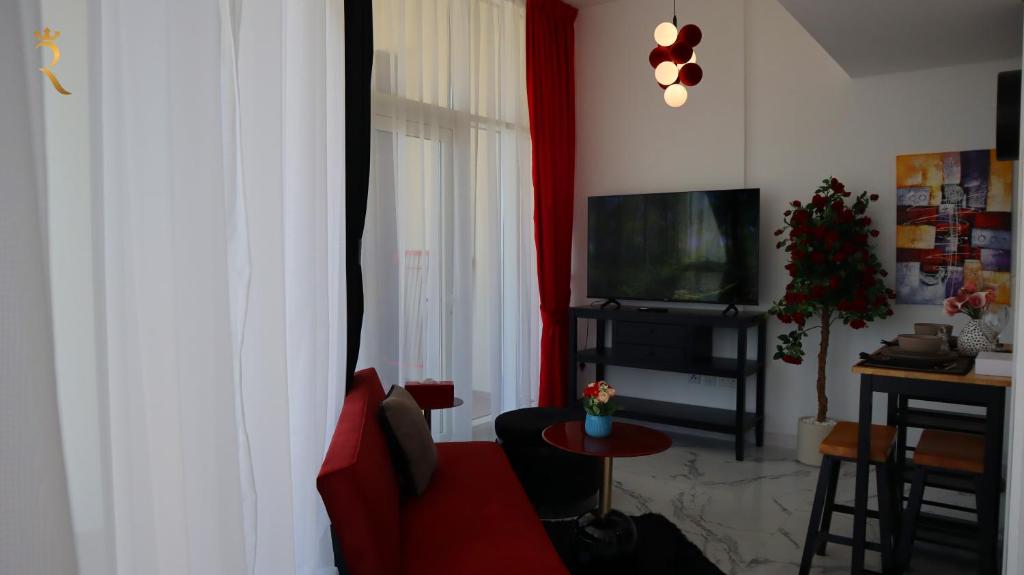 a living room with a red couch and a television at Valentina Studio Transit Apartment in Abu Dhabi