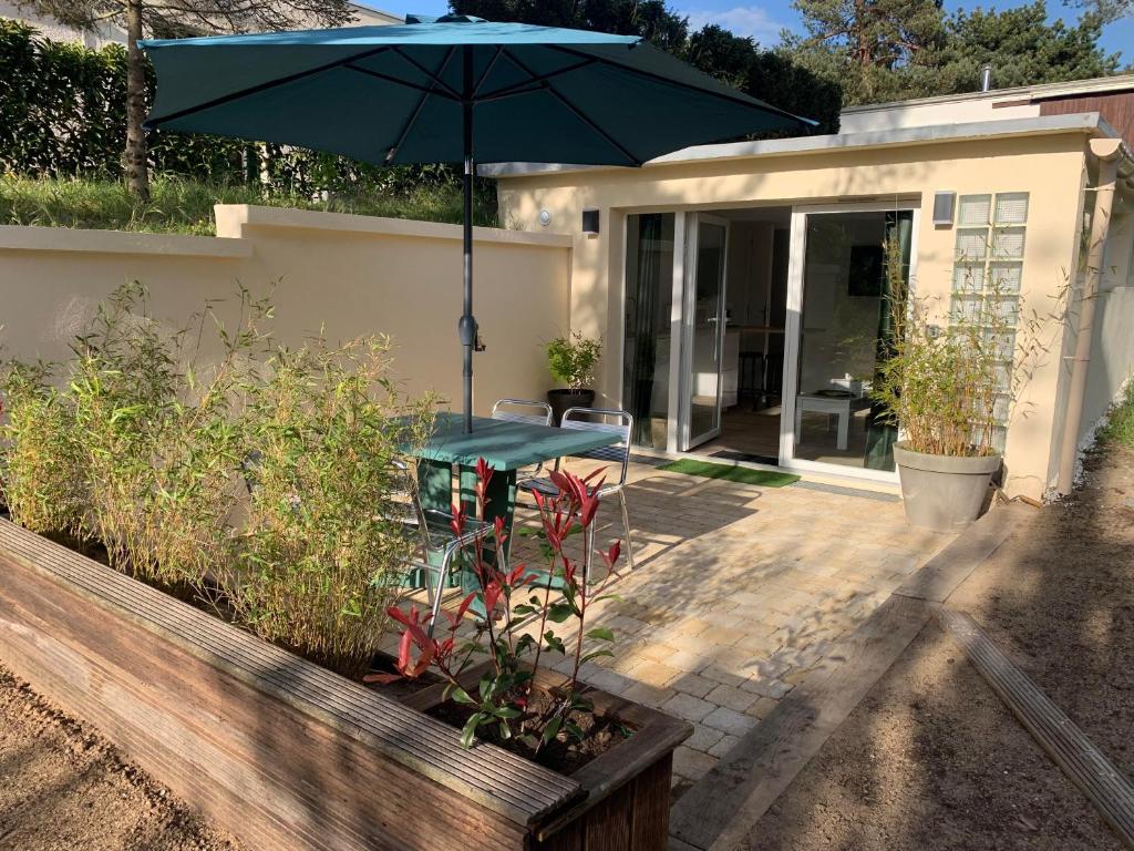 a patio with a table and an umbrella at Dune et Terrasse in Merville-Franceville-Plage