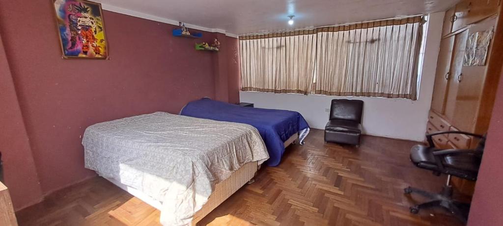 1 Schlafzimmer mit 2 Betten, einem Stuhl und einem Fenster in der Unterkunft Leonel in Puno